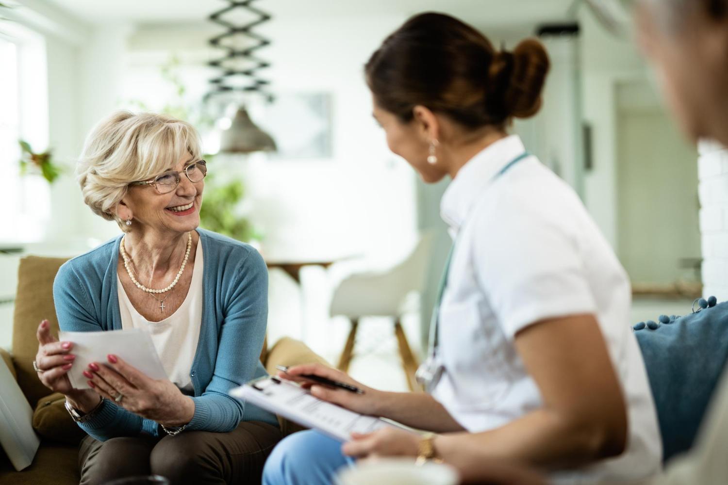 Ein lächelnder Patient spricht mit einer Krankenschwester.